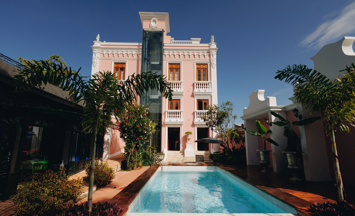 Pink exterior building with a pool and small palmtrees of Quinta das Videiras Hotel